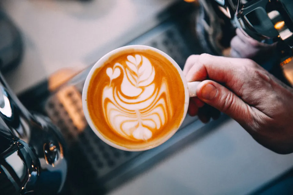 A flat white with latte art being served at the coffee machine