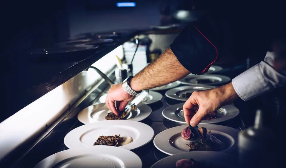 A chef plating dishes in a busy kitchen